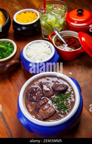 Feijoada brésilienne, cuisine traditionnelle avec diverses viandes de porc accompagnées de chou, riz, caipirinha, farofa Banque D'Images
