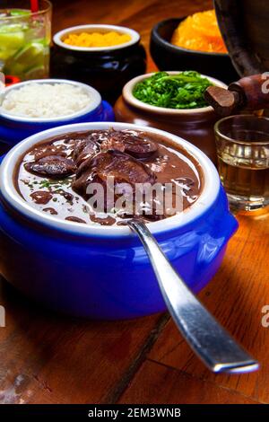 Feijoada brésilienne, cuisine traditionnelle avec diverses viandes de porc accompagnées de chou, riz, caipirinha, farofa Banque D'Images