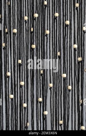 Cordes noires avec perles blanches macrame accrochée sur le mur abstrait arrière-plan Banque D'Images