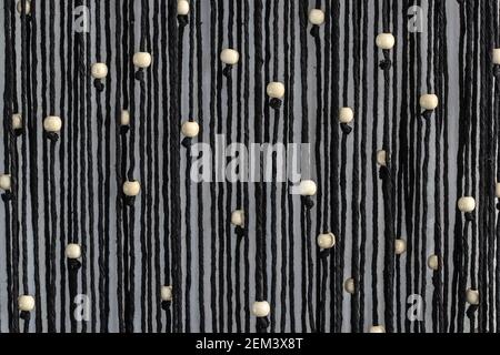 Cordes noires avec perles blanches macrame accrochée sur le mur abstrait arrière-plan Banque D'Images