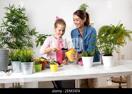 Maman et sa fille préparant toutes les nécessités pour la replantation, du sol aux pots de fleurs, concept de jardinage Banque D'Images