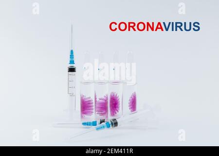 Seringues et ampoules avec un vaccin contre le virus covid-19 avec du texte bleu et rouge Coronavirus sur fond blanc, risque de pandémie. Banque D'Images