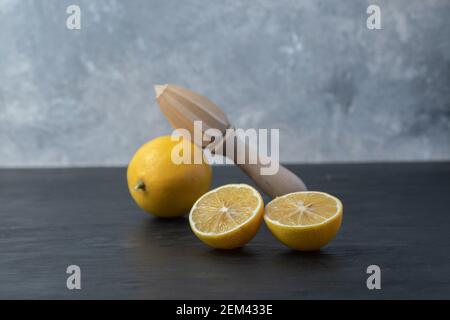 Citron entier et coupé en tranches de jaune frais avec un alésoir en bois Banque D'Images