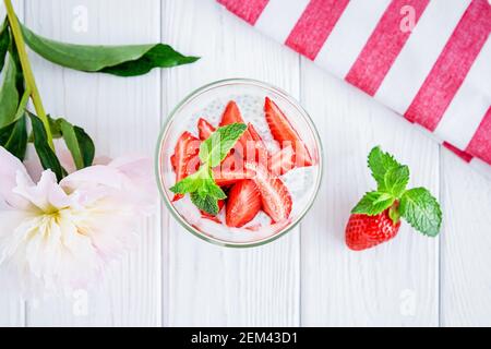 Gâteau au yaourt de Chia avec des fraises fraîches et de la menthe en verre sur fond blanc en bois Banque D'Images