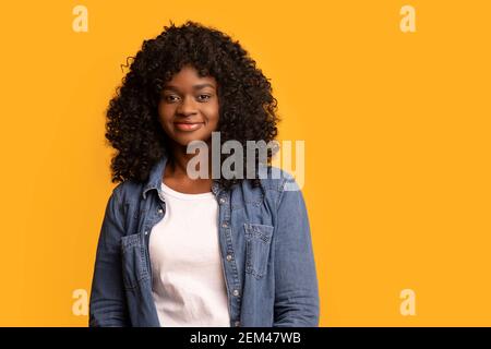 Une jeune femme afro-américaine insouciante pose sur fond jaune Banque D'Images