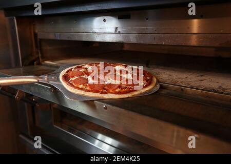 Une pizza au pepperoni mise au four pour la cuisson dans un restaurant Banque D'Images