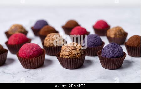 boules d'énergie maison colorées - truffes au cacao, aux myrtilles et à la poudre de betterave. sur fond de marbre Banque D'Images