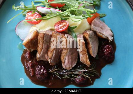 Confit de canard avec salade , pomme au four et sauce aux framboises servi sur table en bois Banque D'Images