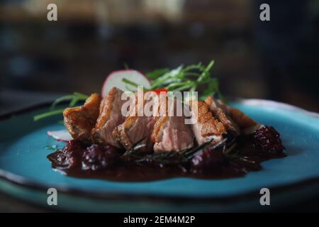 Confit de canard avec salade , pomme au four et sauce aux framboises servi sur table en bois Banque D'Images