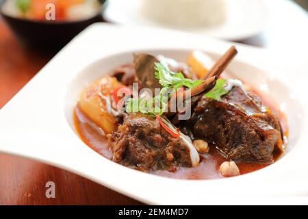 Beef curry massaman avec riz et salade verte sur fond de bois , la nourriture thaïe Banque D'Images