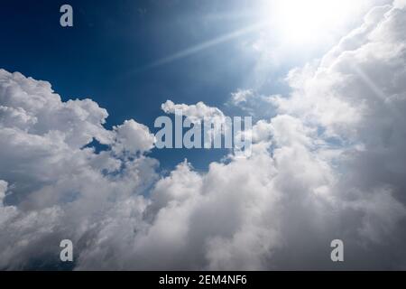 Magnifique ciel bleu avec des cumulus blancs et des rayons du soleil, photographie de contre-jour, Banque D'Images