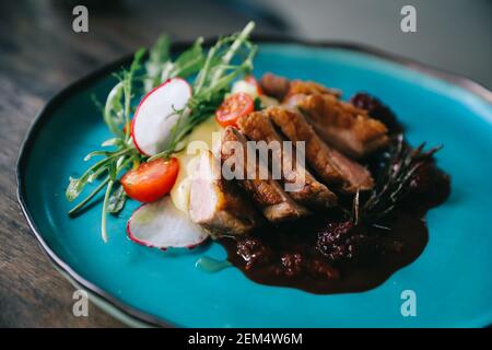 Confit de canard avec salade , pomme au four et sauce aux framboises servi sur table en bois Banque D'Images
