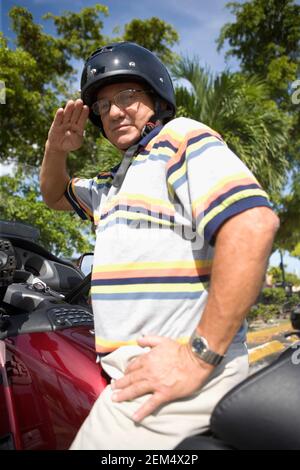 Portrait d'un homme mûr se saluant sur une moto Banque D'Images