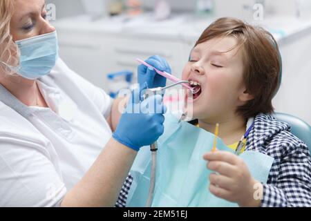 Gros plan d'un jeune garçon qui reçoit un traitement dentaire au fluorure par son dentiste Banque D'Images