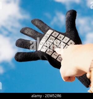 Gros plan d'une personne portant un gant avec des clés de calculatrice imprimé dessus Banque D'Images
