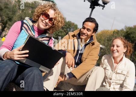 Deux jeunes femmes et un jeune homme assis ensemble et regarder un album photo Banque D'Images