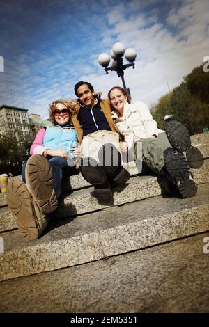 Deux jeunes femmes et un jeune homme assis ensemble étapes Banque D'Images