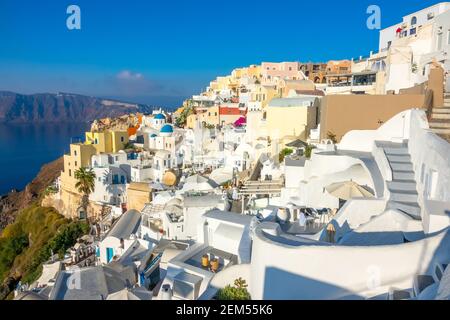 Grèce. Journée d'été ensoleillée à Santorin. Vue sur la mer et les bâtiments et terrasses Oia avec fleurs sur la caldeira Banque D'Images