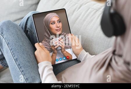 Femme effectuant un appel vidéo avec un ami musulman à l'aide d'une tablette Banque D'Images