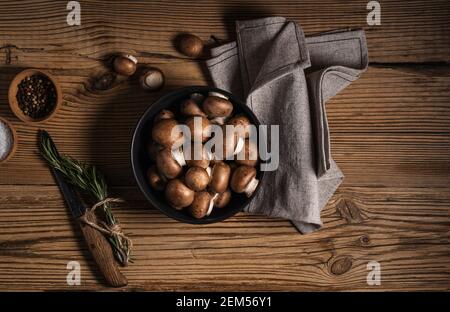 Bol de petits champignons bella et bouquet de romarin frais sur fond rustique en bois, vue d'en haut, nourriture à base de plantes Banque D'Images