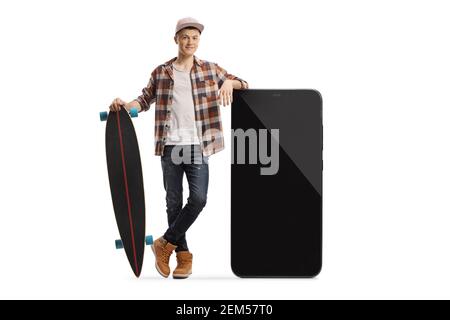 Portrait complet d'un type de patineur qui se penche sur un grand smartphone et tenant un skateboard isolé sur fond blanc Banque D'Images