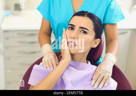 Femme inquiète avec mal de dents touchant la joue dans la clinique dentaire Banque D'Images