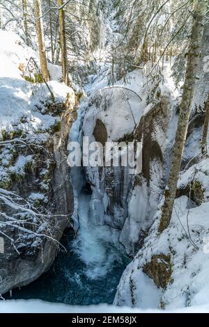 Winter im Bregenzerwald mit vereistem Bach im verschneiten Wald. Hivernent dans la forêt de Bregenz avec un ruisseau glacé dans la forêt enneigée. Cascade et soleil Banque D'Images