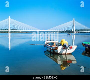 1998 Calvário Estômbar Portugal. Le pont porte la route N125 au-dessus de l'estuaire de l'Arade et est situé dans la ville portugaise de Portimão dans la région de l'Algarve. Il a été inauguré en 1991. Pêcheur dans un petit bateau de pêche apporte sa prise sur la rive à Calvário Estômbar Algarve Portugal eu Europe Banque D'Images