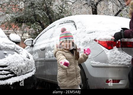 Jolie petite fille attrapant des flocons de neige avec sa main. Mignon garçon jouant dans la neige. Activités d'hiver pour les enfants. Banque D'Images