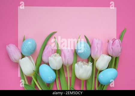 Vacances de Pâques.fleurs de tulipes roses et blanches et œufs décoratifs de Pâques bleus sur fond rose clair. Fond de fête de Pâques dans des couleurs pastel Banque D'Images