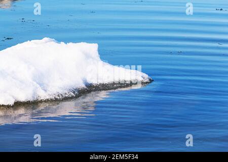 Gros plan d'un grand morceau de glace dans de l'eau bleue. Réchauffement climatique, fonte des glaciers Banque D'Images