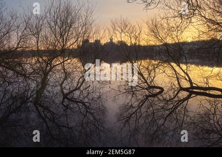 Les arbres au bord du lac se reflètent dans l'eau à l'aube. En arrière-plan, l'ancien château d'Écosse. Palais de Linlithgow, Écosse Banque D'Images