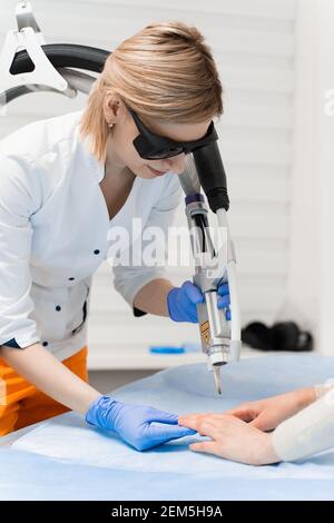 Traitement au laser de l'onychomycose. Infection fongique sur les mains d'une jeune fille en clinique médicale. Banque D'Images