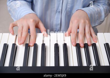 Les mains d'une femme dans une chemise de nuit bleue les touches d'un piano électronique Banque D'Images