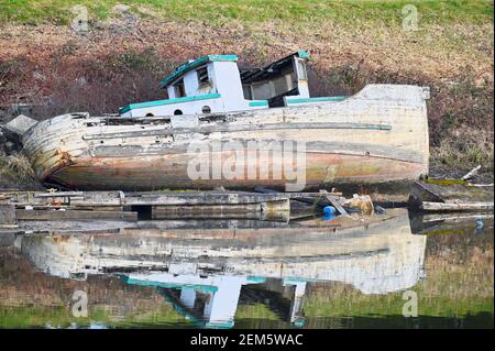 Bateau en bois délabré et abandonné avec réflexion sur la rive de la rivière Pitt, Pitt Meadows, B. C., Canada Banque D'Images