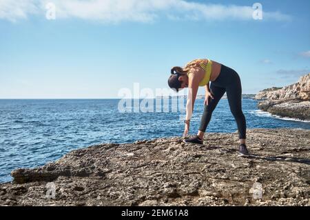 Femme latine d'âge moyen, avec dessus jaune, léopard noir, étirements, gymnastique, réchauffez-vous pour l'entraînement, brûlez des calories, gardez la forme, en plein air Banque D'Images