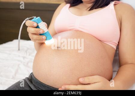 Femme enceinte se sentant heureuse à la maison tout en prenant soin de son enfant. Le jeune s'attend à ce que la mère tient bébé dans le ventre de la grossesse. Maternité prénatale