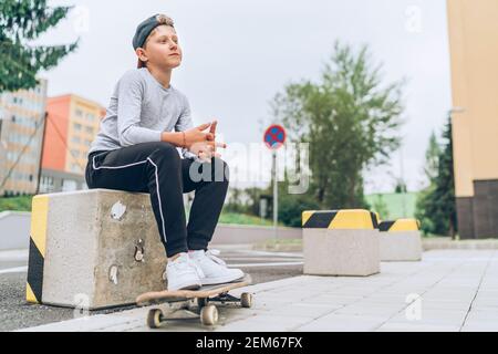 Portrait d'un jeune skateboarder dans une casquette de baseball avec un vieux skateboard dans la rue de la ville. Génération de jeunes passer du temps libre et une population active Banque D'Images