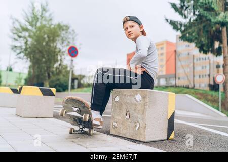 Portrait d'un jeune skateboarder dans une casquette de baseball avec un vieux skateboard dans la rue de la ville. Génération de jeunes passer du temps libre et une population active Banque D'Images