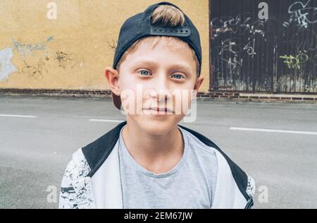 Portrait de mode de cheveux blonds blancs à yeux bleus garçon de 13 ans à skateboarder adolescent dans une casquette de baseball. Génération de jeunes temps libre et Banque D'Images