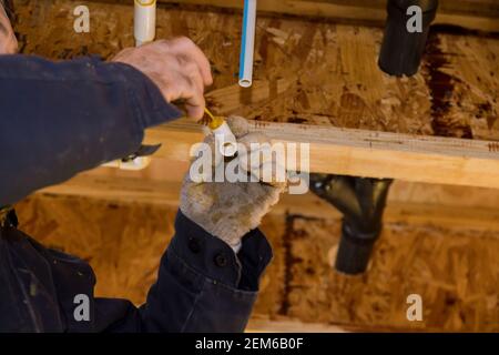 Collage des pièces d'un tuyau d'eau en pvc à l'aide de colle à ciment installation de montage tuyaux en polypropylène de plomberie pour l'eau Banque D'Images