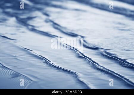 surf vague de mer de près sur une plage après le coucher du soleil, vue en angle bas, ton bleu monochrome Banque D'Images