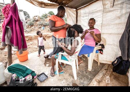 Nairobi, Kenya. 23 février 2021. Les coiffeurs de rue des bidonvilles de Kibera sont vus braiquer leurs collègues dans un saloon local. Crédit : SOPA Images Limited/Alamy Live News Banque D'Images