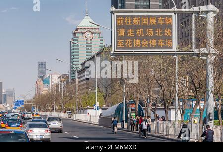 Pékin, Chine - 27 avril 2010 : rue à sens unique avec voitures, bloquée dans la circulation sous un ciel bleu clair. Grande tour d'horloge sur le côté, et peopl Banque D'Images