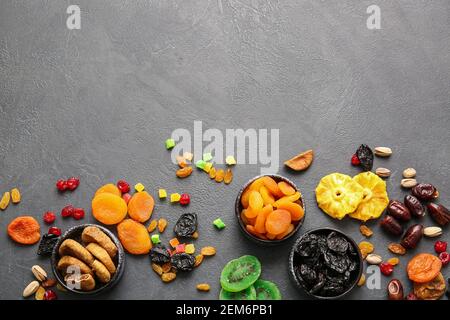 Bols avec différents fruits secs sur fond sombre Banque D'Images