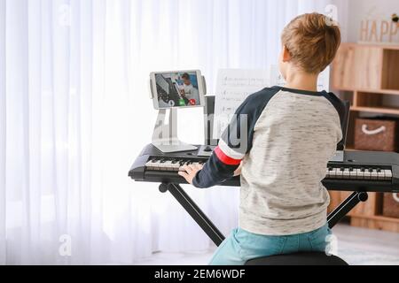 Petit garçon étudiant de la musique avec son ami en ligne à la maison Banque D'Images