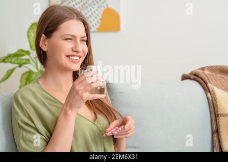 Belle jeune femme prenant des pilules à la maison Banque D'Images