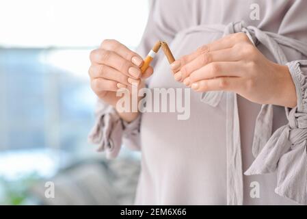 Jeune femme enceinte avec une cigarette cassée, gros plan. Concept de refus de mauvaise habitude Banque D'Images