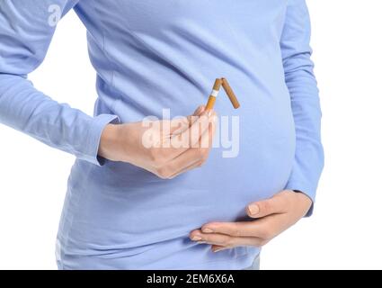 Jeune femme enceinte avec une cigarette cassée sur fond blanc. Concept de refus de mauvaise habitude Banque D'Images