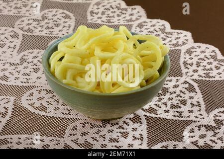 Rondelles d'oignon à l'aneth et à la crème aigre dans un bol en céramique sur le chemin de table rose sur la nappe brune Banque D'Images